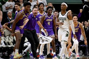 Nov. 6, 2023 ~ Michigan State Spartans guard Tyson Walker walks back to the bench and the James Madison Dukes bench erupts as the final buzzer sounds at the Breslin Center in East Lansing. The Spartans lost in overtime 79-76. Photo: Dale Young ~ USA TODAY SPORTS