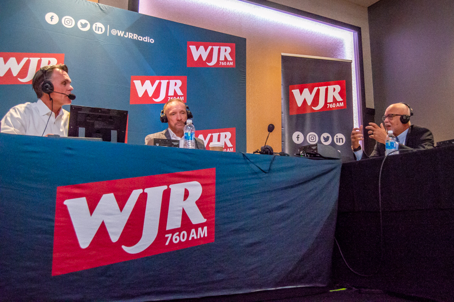 From left to right: Macomb County Executive Mark Hackel, Oakland County Executive Dave Coulter, and Wayne County Executive Warren Evans chat during a live broadcast from the 2024 Detroit Policy conference. Photo: Andrew Mullin ~ 760 WJR