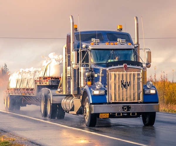 Photo of a truck driving on a rural road at dawn