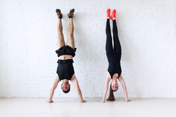 sportsmen woman and man doing a handstand against wall concept balance sport fitness lifestyle and people.