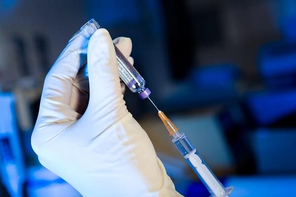 Scientist using syringe sucking vaccine, white gloves, blue background