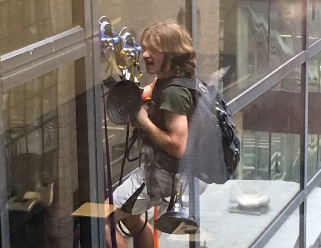 A man is scaling Trump Tower using giant suction cups.