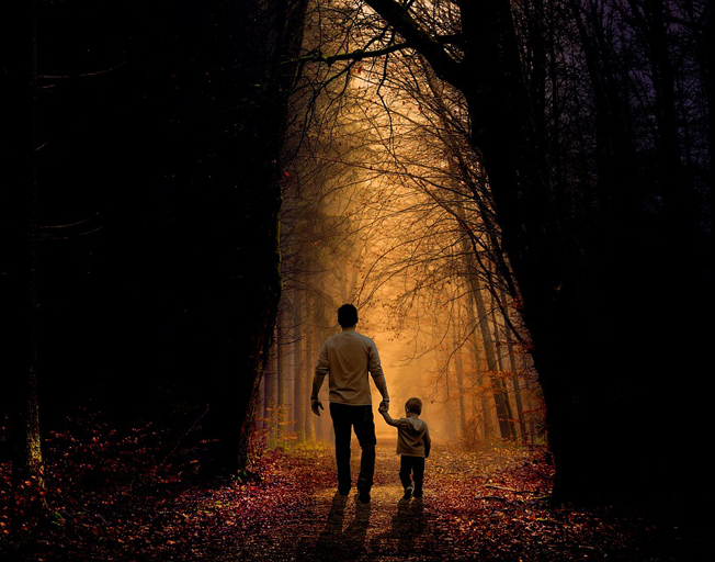 A father and child walking on a path in the woods