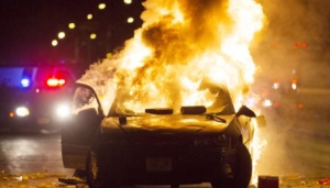 A car burns as a crowd of more than 100 people gathers following the fatal shooting of a man in Milwaukee, Saturday, Aug. 13, 2016. The Milwaukee Journal Sentinel reported that officers got in their cars to leave at one point, and some in the crowd started smashing a squad car's window, and another vehicle, pictured, was set on fire. The gathering occurred in the neighborhood where a Milwaukee officer shot and killed a man police say was armed hours earlier during a foot chase. (Calvin Mattheis/Milwaukee Journal-Sentinel via AP)