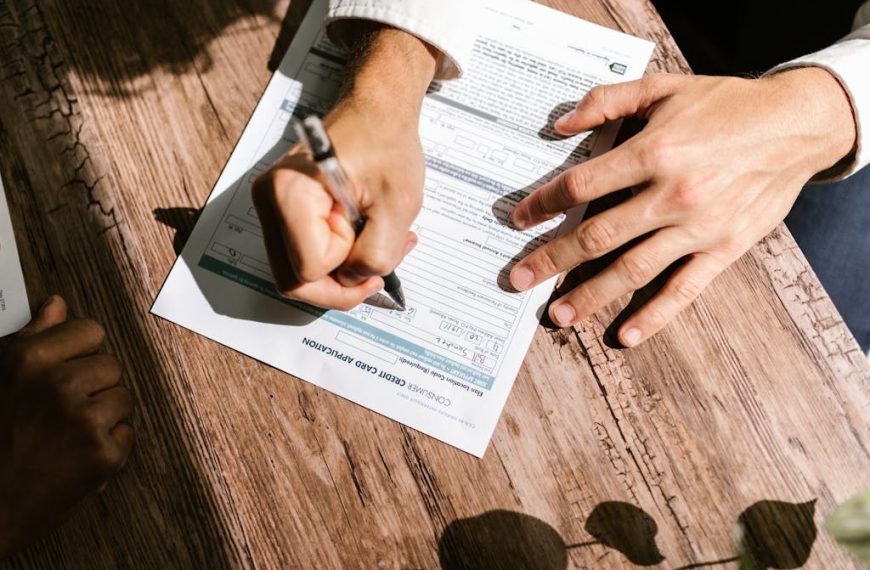 Hands writing on a consumer loan credit application form on a wooden table.