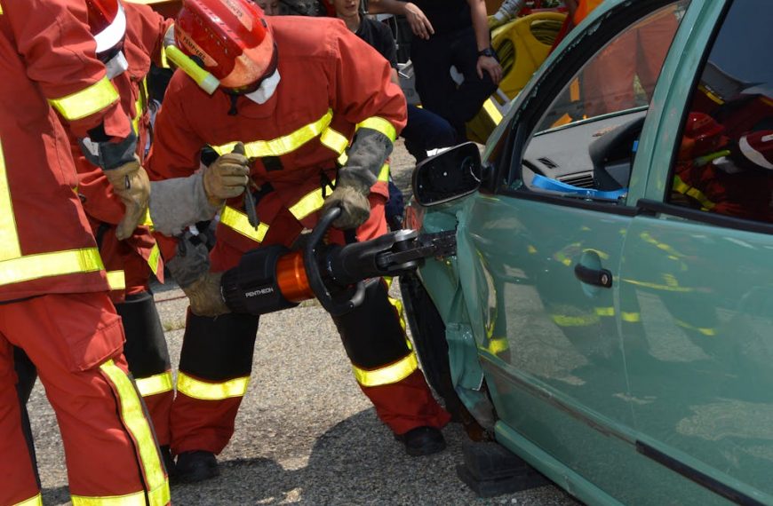 Firefighters demonstrate rescue techniques using a hydraulic cutter at a car crash practice session.