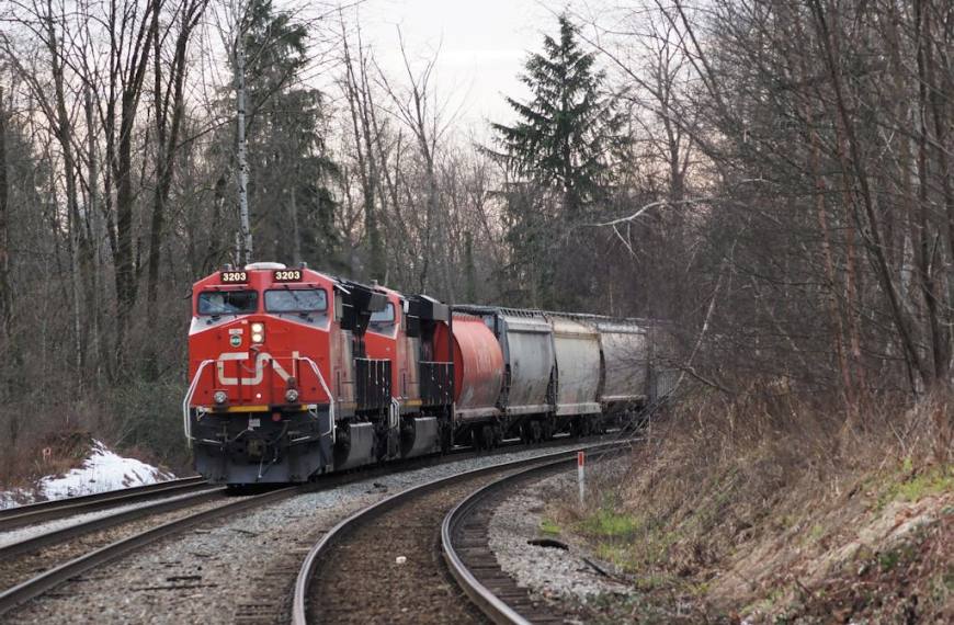 A freight train travels through a forested area in Burnaby, BC during winter.