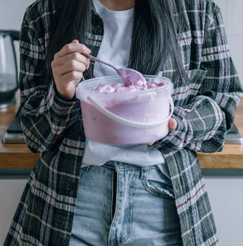 A Sad Woman by the Kitchen Counter Holding a Pail of Ice Cream